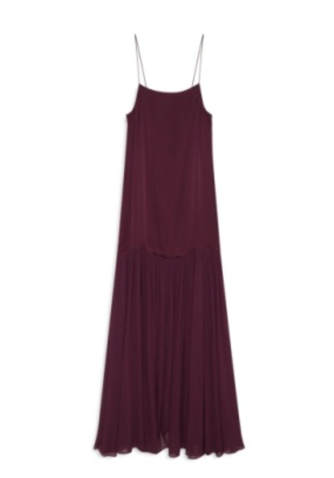 The Clementine Dress by Anine Bing is a sleeveless, burgundy satin dress designed with thin spaghetti straps and a drop waist, showcasing a modern silhouette and a flowing, pleated lower skirt.