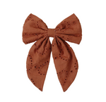 The Noralee Girls' Everly Bow features brown embroidered eyelet details, two long tails, and a rose gold alligator clip—creating a charming hair accessory for girls. Shown on a white background.