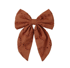 The Noralee Girls' Everly Bow features brown embroidered eyelet details, two long tails, and a rose gold alligator clip—creating a charming hair accessory for girls. Shown on a white background.