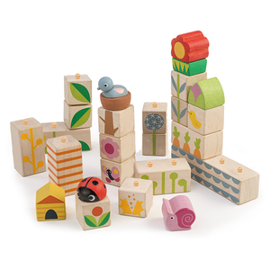 Garden Blocks by Tender Leaf Toys feature wooden toy blocks with painted designs—including a bird, ladybug, snail, bee house, and floral patterns inspired by garden shapes—that can be arranged in various stacks and structures to help develop hand-eye coordination.
