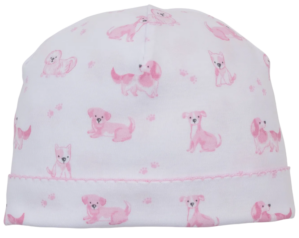 The Kissy Kissy Puppy Paws Printed Hat is crafted from ultra-soft Pima cotton and showcases a charming pattern of small pink cartoon puppies and puppy paws scattered across the fabric.