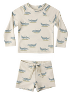 The Rylee & Cru Baby Boys' Rashguard Set includes a cream-colored long-sleeve top and shorts with a green and blue alligator print.