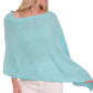 A woman in an Alashan Cashmere turquoise Cashmere Dress Topper Poncho, perfect for day-to-night wardrobe.