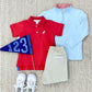 Children’s outfit on a textured rug showcasing a red polo, khaki pants, white sneakers, a blue pennant with 123, and The Beaufort Bonnet Company’s Baby Boys' and Boys' Hayword Half Zip pullover in Buckhead Blue.
