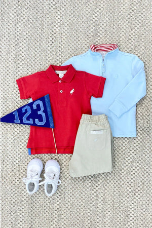 Children’s outfit on a textured rug showcasing a red polo, khaki pants, white sneakers, a blue pennant with 123, and The Beaufort Bonnet Company’s Baby Boys' and Boys' Hayword Half Zip pullover in Buckhead Blue.