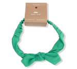 The Angel Dear Knot Headband is a green baby accessory featuring a knotted bow and comes with a brown cardboard tag—ideal for adding charm to any fall or winter wardrobe.