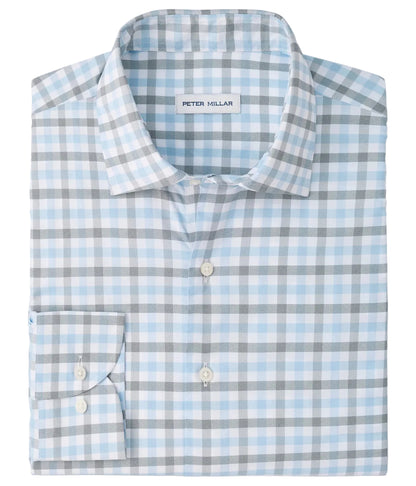A neatly folded Lucas Performance Twill Sport Shirt by Peter Millar, featuring long sleeves and a button-down design with a light blue, grey, and white plaid pattern. Crafted from performance fabric, this shirt seamlessly blends style and comfort for any occasion.