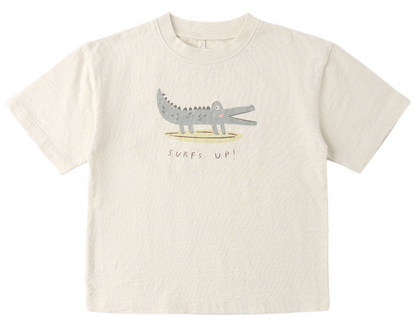 The Rylee & Cru Baby Boys' and Boys' Relaxed Tee is a beige cotton jersey shirt with a cartoon crocodile and “Surfs Up!” text, offering a comfortable fit for easy dressing.