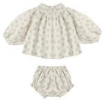 The Baby Girls’ Quincy Set from Rylee & Cru includes a long-sleeve blouse with elastic neck and cuffs, paired with a coordinating bloomer. Both pieces feature a light grey floral print on an off-white background for a timeless, delicate style.