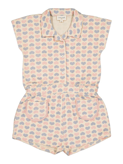 Girls’ Lola Terry Heart Overall by Louis Louise: a short-sleeve terrycloth romper featuring a collar, button front, and pockets, adorned with pastel pink, blue, and beige hearts on textured fabric.
