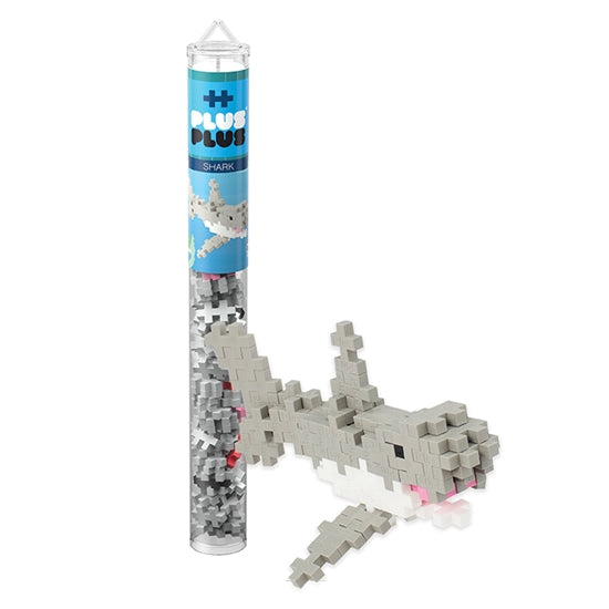 A Plus Plus Tube - Shark stands beside a finished gray and white shark model, encouraging creative play and helping to develop fine motor skills.