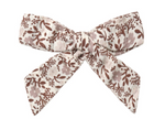 The Rylee & Cru Girls’ Bow, featuring brown floral and leaf patterns on an off-white background and secured with an alligator clip, adds a charming touch when displayed alone against a white surface.