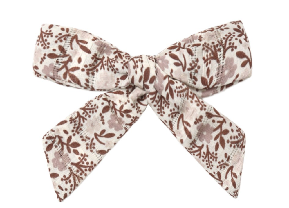 The Rylee & Cru Girls’ Bow, featuring brown floral and leaf patterns on an off-white background and secured with an alligator clip, adds a charming touch when displayed alone against a white surface.
