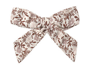 The Rylee & Cru Girls’ Bow, featuring brown floral and leaf patterns on an off-white background and secured with an alligator clip, adds a charming touch when displayed alone against a white surface.