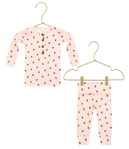 The Lou Lou & Company Baby Girls’ and Girls’ Junie Top & Bottoms set includes a silky-soft, long-sleeve Henley top adorned with a charming strawberry pattern and matching pants, both showcased on gold hangers against a white background.
