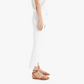 Someone wearing Mother’s The Insider Crop Step Fray and brown strappy sandals stands sideways on a white background.