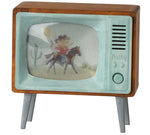 The Maileg Television - Mouse is a charming vintage toy television, perfect for Mouse Hole Farmhouse, featuring a painted image of a cowboy riding a horse in a desert scene displayed on the screen—an ideal addition to your collection of miniature mouse accessories.