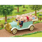 A Classic Family Car by Calico Critters, featuring seating for up to 10 figures, carries several plush bear figurines along a dirt path in a green park with trees and a wooden fence, and comes complete with charming toy car accessories.