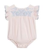 The Louise Misha Baby Girls’ Nusha Romper is crafted from soft cotton gauze in a light pink hue, featuring short ruffled sleeves, an embroidered yoke with delicate blue floral detailing on the chest, and convenient snap closures at the bottom.