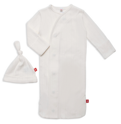 The Magnetic Me Baby Love Lines Gown + Hat Set is a white long-sleeve newborn outfit with side snap buttons, matching knot-top hat, subtle vertical stripes, red fabric tags, and made from soft organic cotton for your baby's comfort.