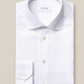 The Eton White Signature Twill Shirt, Slim Fit, features a classic collar and buttoned cuffs with the brand label inside, offering a versatile and impeccable look. Elegantly displayed on a beige background.