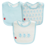 The Magnetic Me Baby Trunkettes Modal Bib 3-Pack includes three absorbent bibs with light blue trim: one in solid blue, one featuring a blue ballerina pattern, and one with three blue ballerinas. Each bib is finished with a small red tag on the left side.
