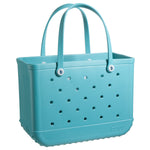 Image of a light blue plastic Original Bogg Bag with perforations and two handles. The bag features the brand name "Bogg Bags" embossed near the bottom and small circular buttons near the handle bases, showcasing its stylish yet washable design.