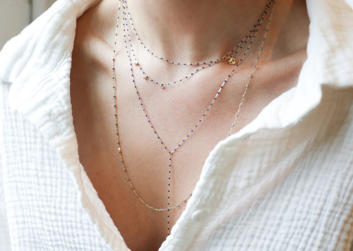 Close-up of a person wearing a white textured shirt, highlighted by the Gigi Clozeau Party Y Necklace 19.7" layered with delicate chains.