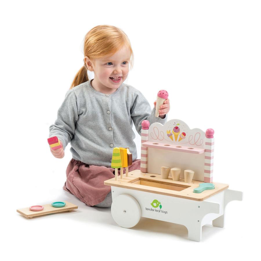 A little girl playing with a Tenderleaf Ice Cream Cart from Tender Leaf Toys, enjoying the magic of delicious ice cream treats.