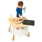 A young boy playing with a stylish Tenderleaf Forest Table by Tender Leaf Toys and a bottle.