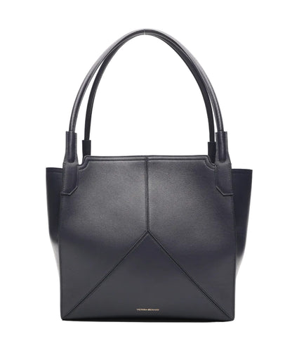 A Small Victoria Tote by Victoria Beckham in black smooth calf leather, featuring double handles, geometric stitching, and small gold text near the lower center, shown on a plain white background.