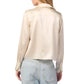 Rear view of a person wearing a cream-colored Yves Silk Button Down Top by Sablyn, paired with light blue jeans against a white background.