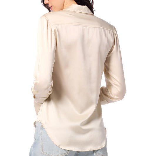 A person is shown from the back, wearing a long-sleeved, light beige Sablyn Vincent Silk Shirt and light blue jeans. The person’s left hand is in their pocket.