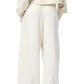 A person wearing a cream-colored long-sleeve top and Sablyn's Hayes Sweatpant, standing with hands in pockets, facing away.