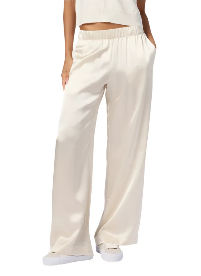 A person wearing elegant cream-colored Sablyn Brynn Silk Pants and a sleeveless top.