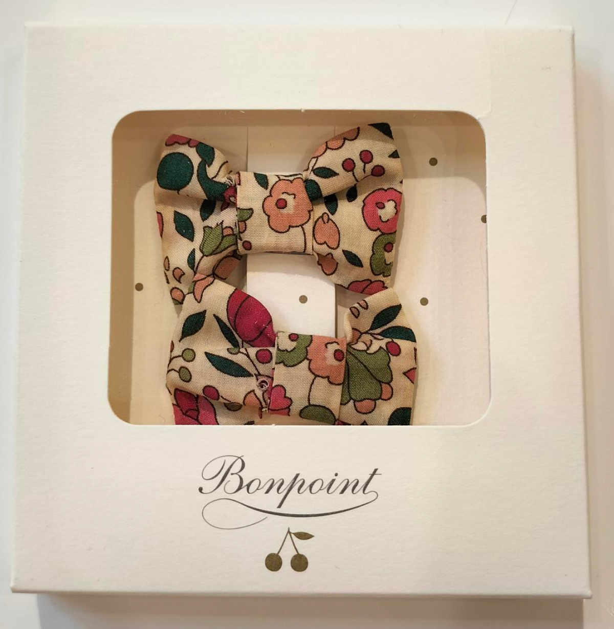 The Miniclic Barette by Bonpoint features a floral-patterned Liberty Tana Lawn fabric bow, beautifully presented in a square white box with a clear window and the signature cherry logo on the front—perfect for adding charm to any girl’s hair clip collection.
