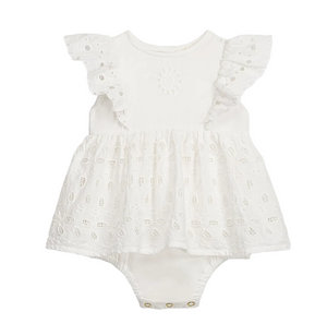 The Louise Misha Baby Girls’ Lenali Romper is a white cotton dress-style romper adorned with delicate eyelet embroidery on the ruffled sleeves, a gathered skirt, and convenient snap buttons at the bottom.