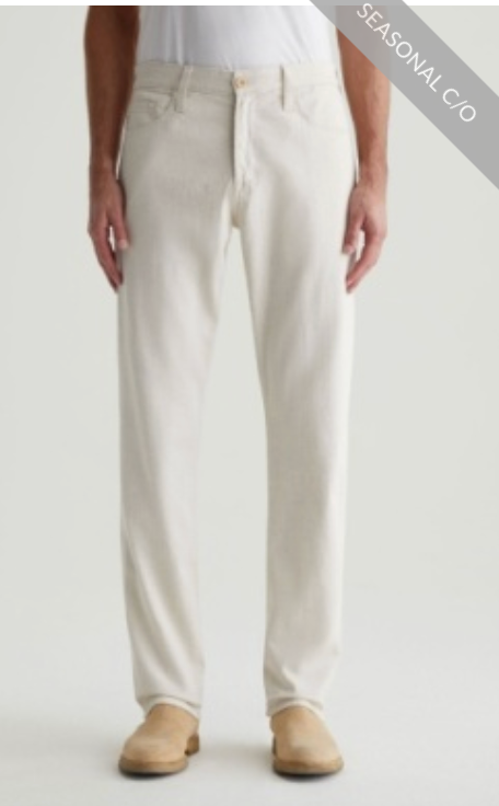 A person wearing AG Jeans' Everett Slim Straight light beige twill linen pants and tan shoes stands against a plain background. A banner in the top right corner reads "SEASONAL C/O.