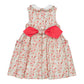 The Kidiwi Baby Girls' and Girls' Ixia Smocked Dress features a sleeveless cotton design with a white collar, front buttons, two side pockets, and a large pink bow tied at the back.
