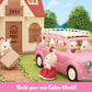 Calico Critters toy rabbit figures stand beside a pink Calico Critters Family Picnic Van and house, with one rabbit carrying luggage and picnic accessories. Text at the bottom reads, “Build your own Calico World!”.