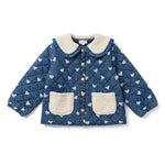The Girls’ Carda Jacket by Louis Louise is a blue quilted denim jacket for kids, featuring a charming white heart print, cozy white faux fur collar and pockets, and gold buttons down the front.