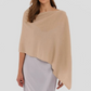 A woman models the Alashan Cashmere Dress Topper Poncho in light beige, layered over a light lavender satin dress—demonstrating this versatile wardrobe essential against a plain background.