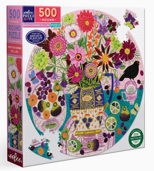 Eeboo’s Fruits & Flowers Still Life 500-Piece Round Puzzle is a vibrant, round jigsaw inspired by Vanessa Bowman, showcasing a colorful floral still life with flowers in a vase, fruits, a black bird, and small decorative items on a crisp white background—evoking the charm of a painted masterpiece.
