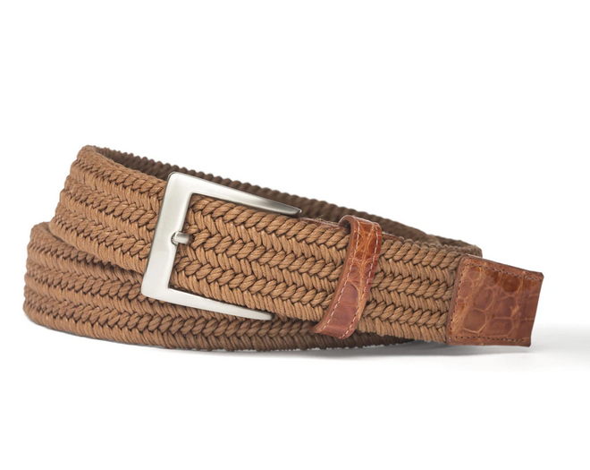 The Men's Solid Stretch Belt with Croc Tabs by W. Kleinberg features a coiled brown weave, silver rectangular buckle, and comfortable leather accents at the tip and buckle area, displayed against a white background.