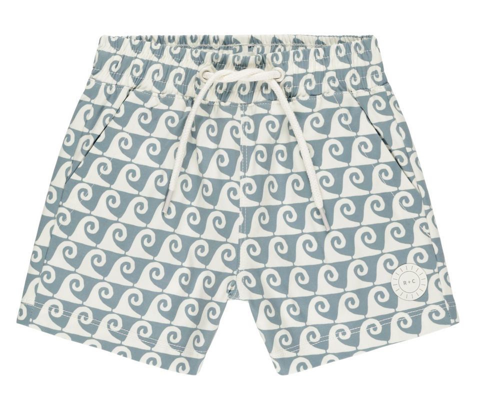 The Rylee & Cru Boys' Board Short features a blue and white wave pattern, elastic waistband with drawstring, side pockets, and a small circular logo on the left leg—ideal for coordinated swimwear looks.