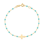 The Gigi Clozeau Classic Cross Charm Bracelet 6.7" showcases a stunning blend of turquoise beads, an 18 carat gold chain, elegant resin pearls, and a central cross charm.