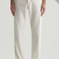 A person models the AG Jeans Everett Slim Straight, featuring a mid-rise waist in an off-white shade, paired with tan shoes and set against a plain background. A "SEASONAL C/O" banner is displayed in the top right corner.