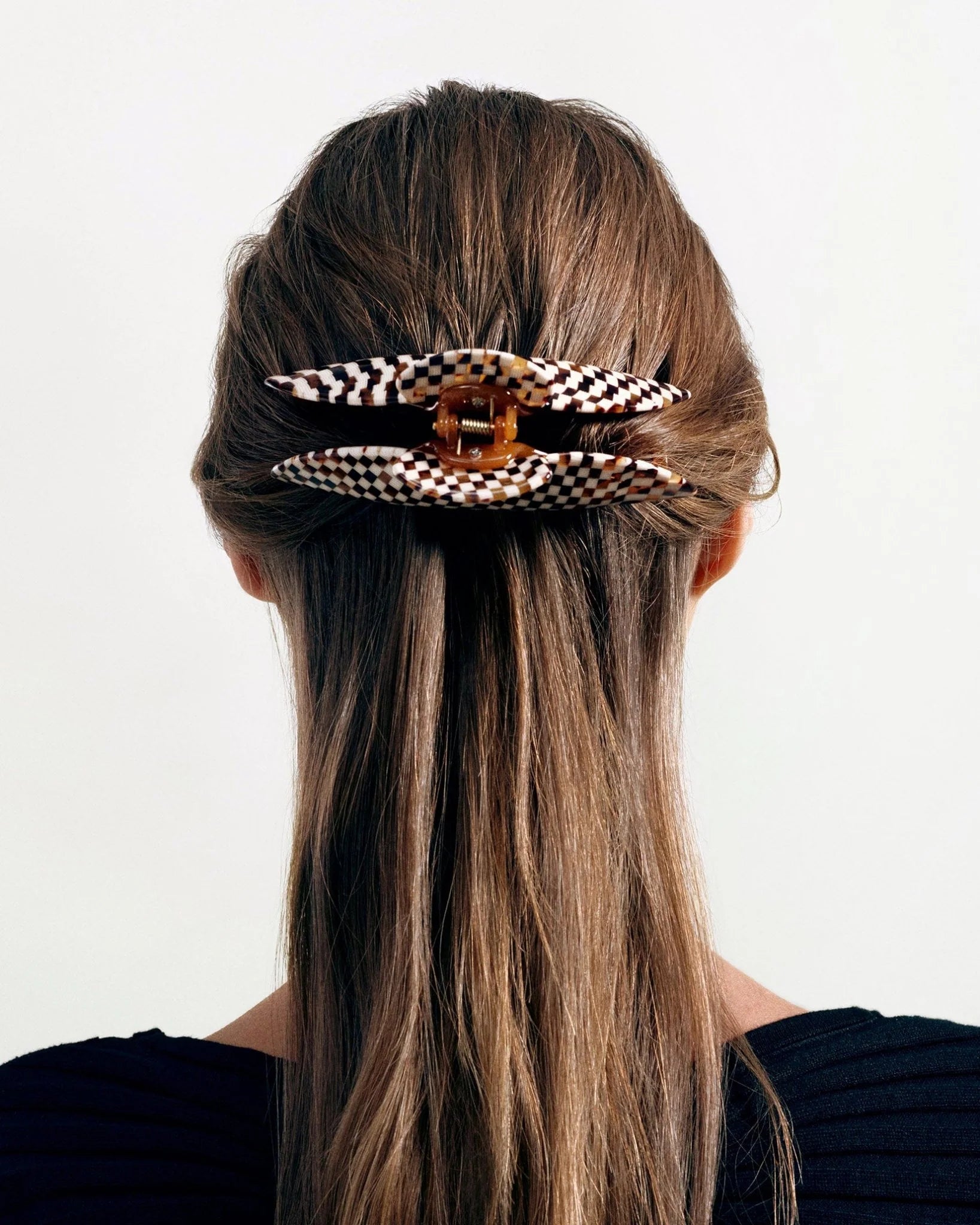 A person with long, straight brown hair is wearing two Machete Jumbo Heirloom Claws made from Italian acetate at the back of their head.