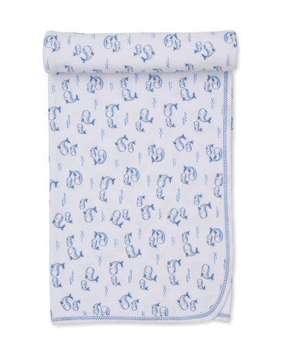 Kissy Kissy Whale Pods Blanket—white Pima cotton baby blanket featuring blue embroidered letters and charming whale designs, rolled at the top and neatly folded at the corner—a soft and cozy choice perfect for little ones.