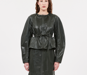 Against a plain white background, a person wears the Aidan Jacket by Ulla Johnson, featuring a collarless neckline in rich jasper green napa leather and a stylish belt.